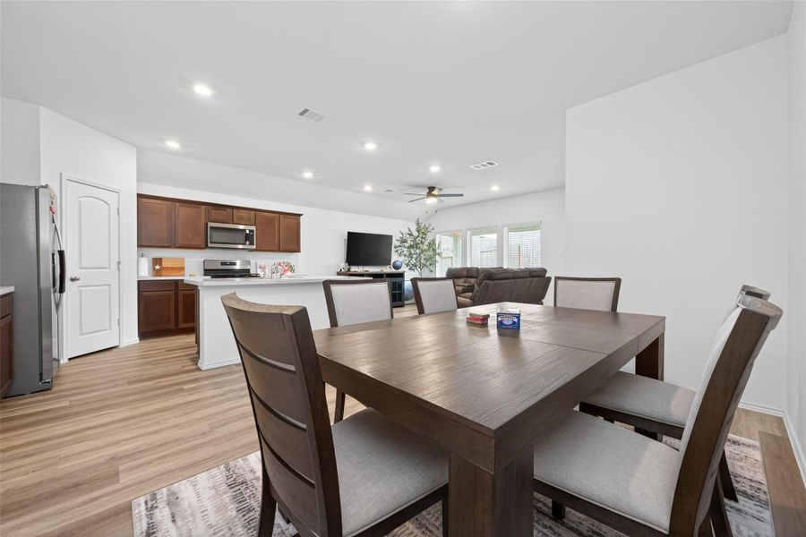 Spacious, open-concept living area with a modern kitchen, featuring stainless steel appliances and dark cabinets.