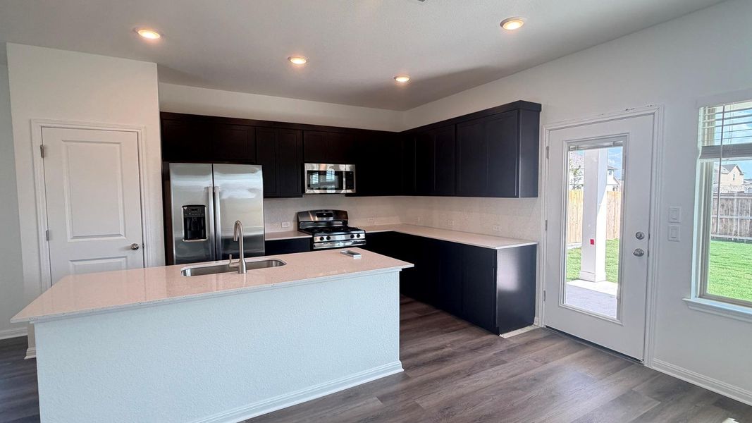 A well-appointed kitchen features dark cabinetry, stainless steel appliances, and a central island, complemented by sleek flooring. A well-appointed kitchen features dark cabinetry, stainless steel appliances, and a central island, complemented by sleek flooring.