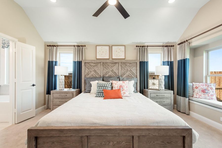 Bedroom with king-size wood bed frame, vaulted ceiling, ceiling fan, and window seat Bedroom with king-size wood bed frame, vaulted ceiling, ceiling fan, and window seat