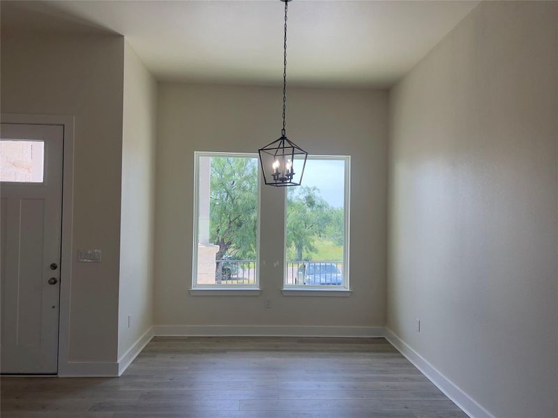 Natural light fills this dining area, featuring sleek wood flooring and a modern chandelier.