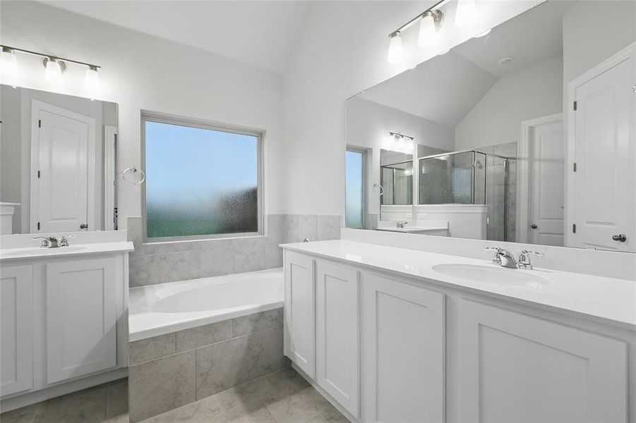 Full bath featuring a stall shower, two vanities, a bath, light tile patterned floors, and lofted ceiling Full bath featuring a stall shower, two vanities, a bath, light tile patterned floors, and lofted ceiling