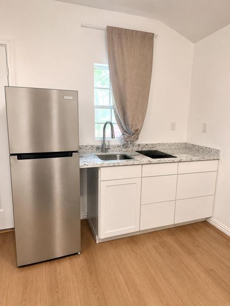 A compact kitchen boasts granite counters, stainless steel appliances, and sleek cabinetry for efficient living.
