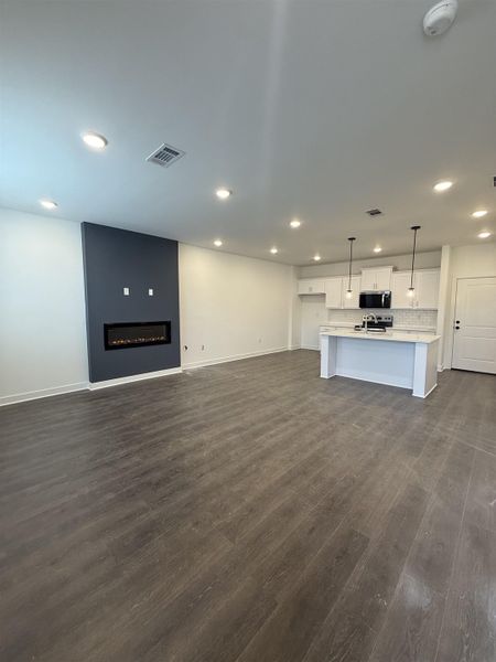 Unfurnished living room featuring dark wood-style floors, recessed lighting, and a fireplace