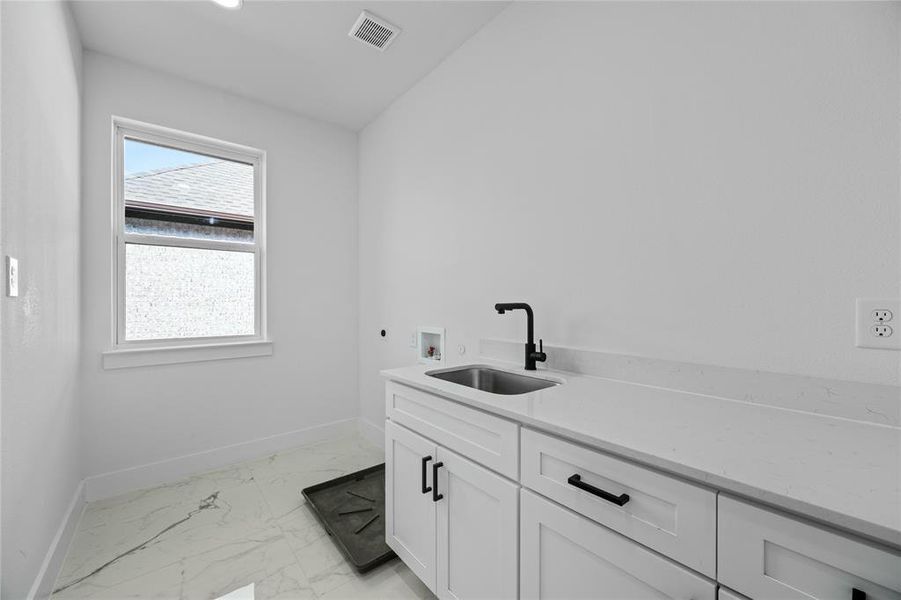 Laundry area with washer hookup, electric dryer hookup, light marble finish flooring, and cabinet space