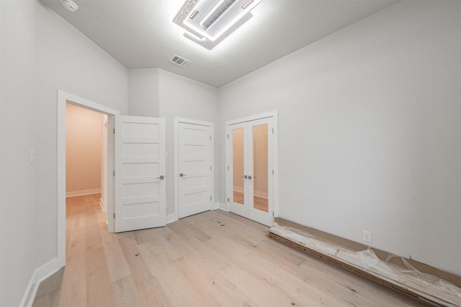 Unfurnished room featuring light wood-style flooring, french doors, and cooling unit