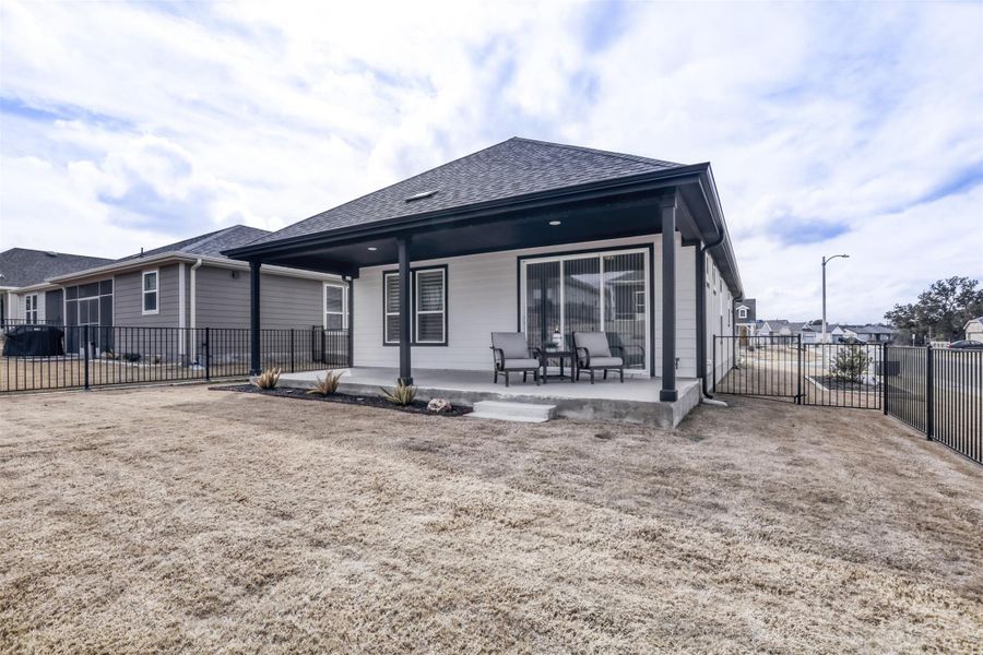 Back of property featuring a gate, a patio area, and roof with shingles
