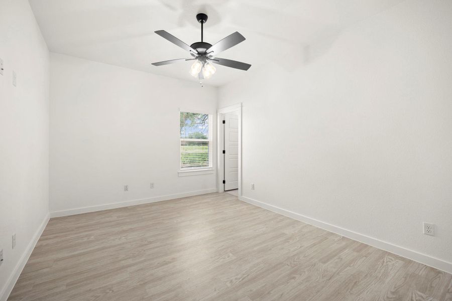 Bright and airy, this bedroom provides a tranquil retreat with wood-look flooring and an overhead ceiling fan.