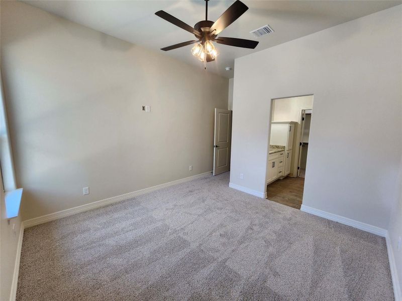 Unfurnished bedroom featuring light colored carpet, ceiling fan, and connected bathroom