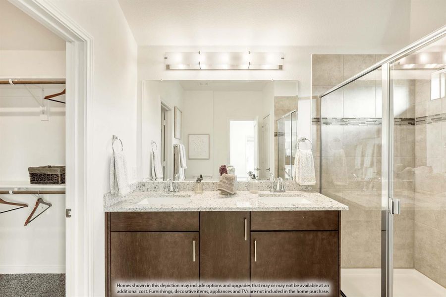 Master bathroom with double vanity, granite countertops, glass shower, and walk-in closet entrance