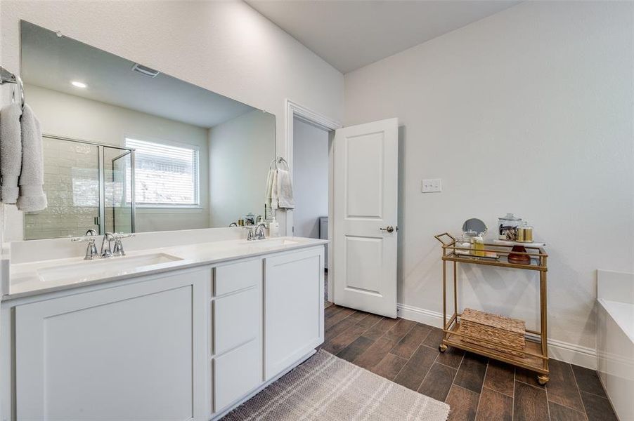 Primary bathroom with dual vanities and storage.