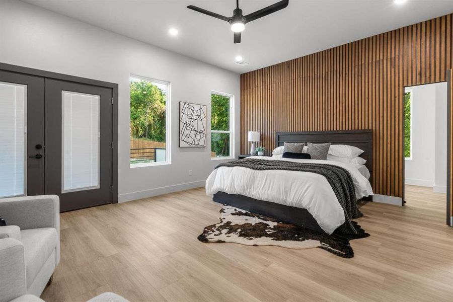 Bedroom with an accent wall, french doors, light wood finished floors, a ceiling fan, and access to outside