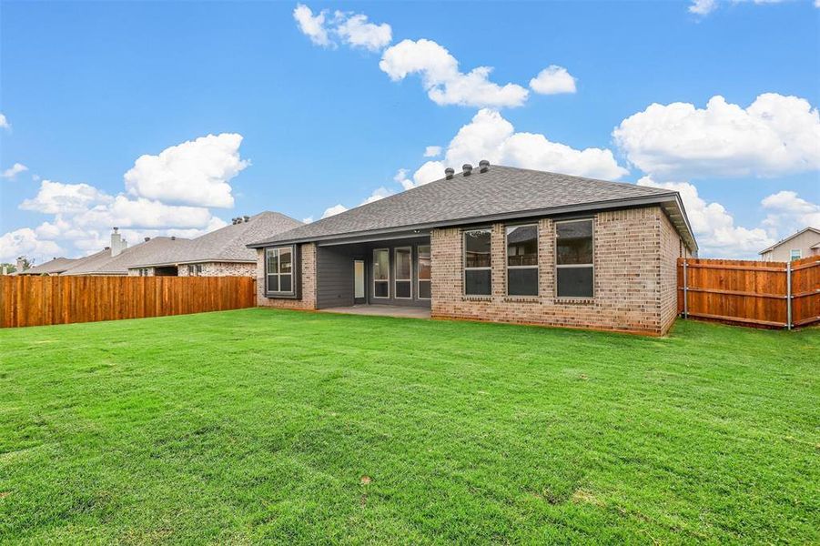 Rear view of house featuring a lawn and a patio