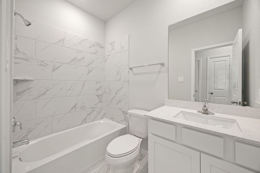 The secondary bathroom offers tile flooring, a bath/shower combination with a stylish tile surround, white stained wood cabinetry, elegant light countertops, a mirror, and sleek fixtures with modern finishes. The secondary bathroom offers tile flooring, a bath/shower combination with a stylish tile surround, white stained wood cabinetry, elegant light countertops, a mirror, and sleek fixtures with modern finishes.