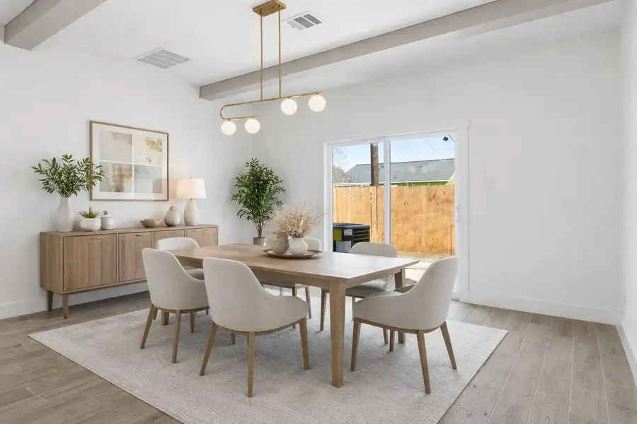 The dining room boasts luxury vinyl flooring, a stylish gold light fixture, and sliding doors that open to the backyard. (staged)