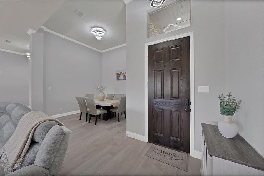 Foyer with crown molding, baseboards, and light wood-style flooring Foyer with crown molding, baseboards, and light wood-style flooring