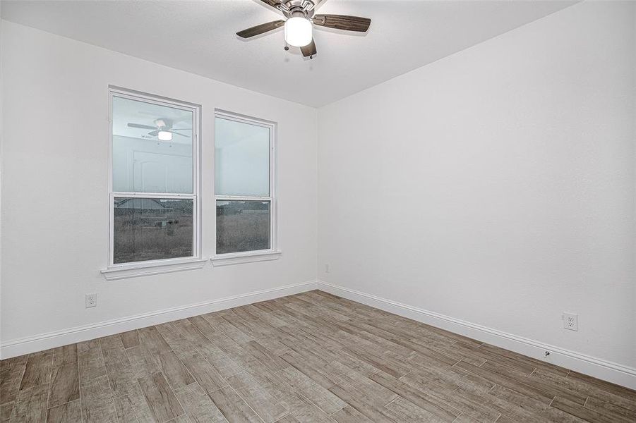 Empty room with a ceiling fan, wood finished floors, and baseboards Empty room with a ceiling fan, wood finished floors, and baseboards
