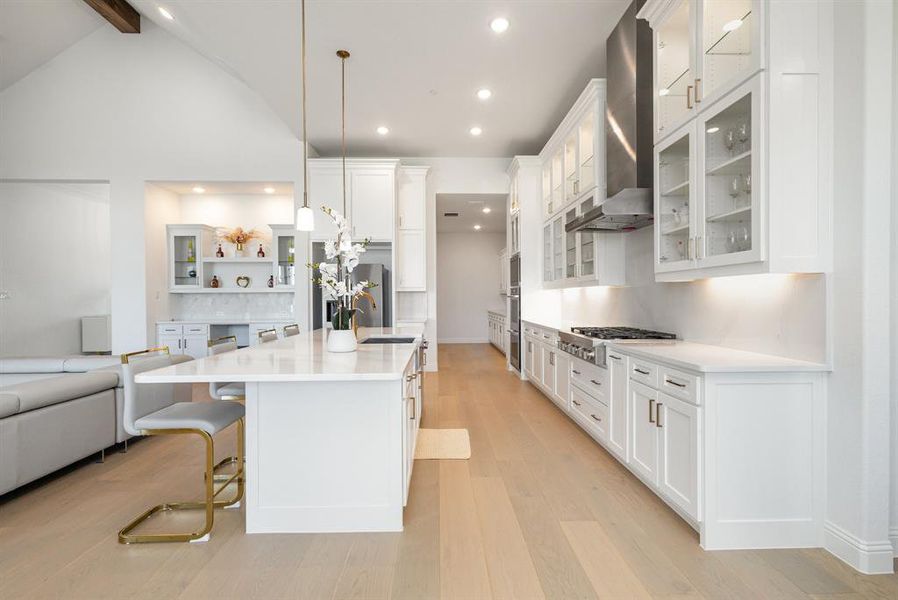 Kitchen with white cabinets, glass insert cabinets, a breakfast bar, and recessed lighting