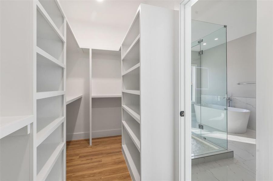 Walk in closet with hardwood / wood-style flooring