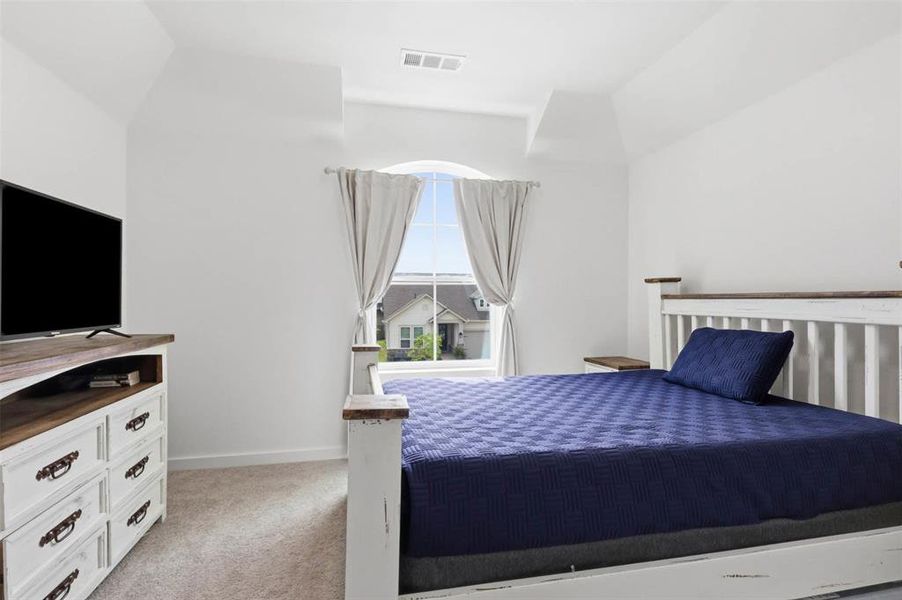 Arched window with residential scenery, white walls, and light-colored carpet flooring