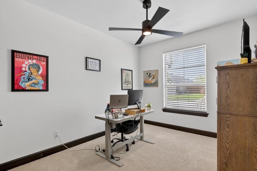 Carpeted room with a ceiling fan, a window with horizontal blinds, and dark wood-finish trim