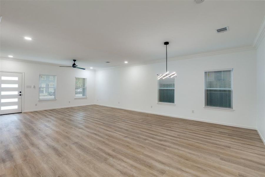Unfurnished living room featuring ceiling fan, light wood-type flooring, crown molding, and recessed lighting Unfurnished living room featuring ceiling fan, light wood-type flooring, crown molding, and recessed lighting