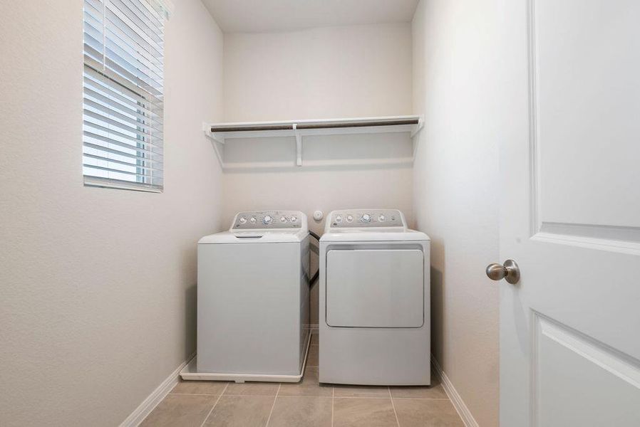 Laundry area with washer and dryer and light tile patterned flooring