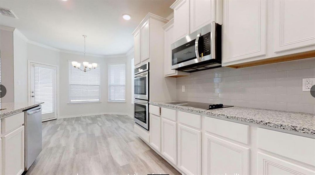 Kitchen featuring appliances with stainless steel finishes, a chandelier, white cabinetry, tasteful backsplash, and light wood-style flooring