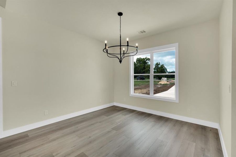 Empty room featuring an inviting chandelier and light hardwood / wood-style floors