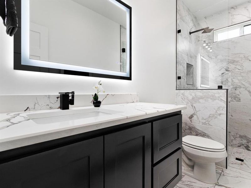 Modern bathroom featuring a dark vanity with panel-front cabinetry, a white countertop with integrated sink, and a black faucet