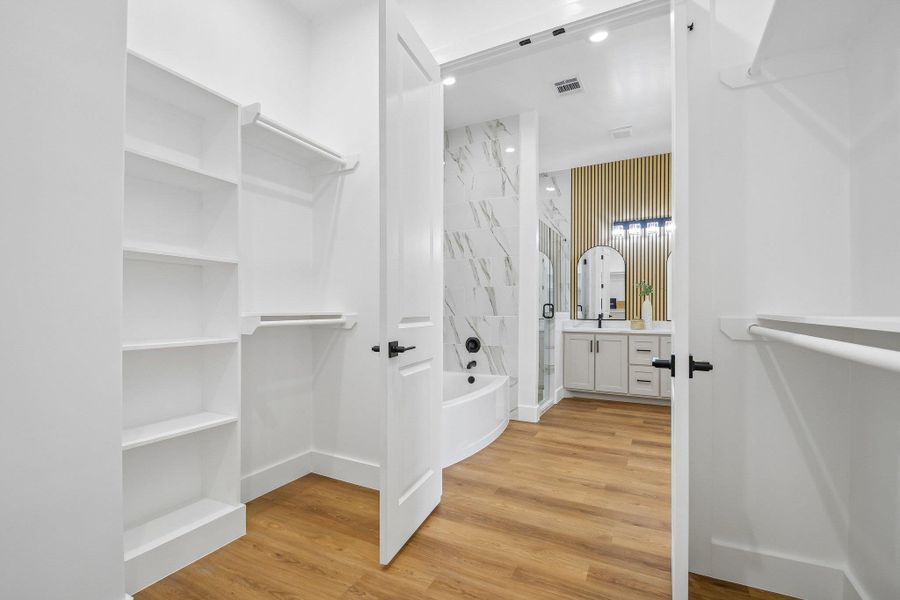 Ample built-in shelving and custom hanging racks define this spacious walk-in closet with warm wood-look floors. Ample built-in shelving and custom hanging racks define this spacious walk-in closet with warm wood-look floors.