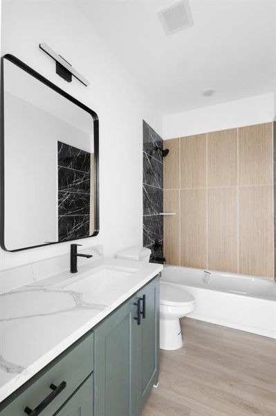 Bathroom with wood finished floors, vanity, toilet, shower / bathtub combination, and visible vents Bathroom with wood finished floors, vanity, toilet, shower / bathtub combination, and visible vents