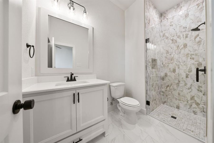 Full bath featuring vanity, a stall shower, and light marble finish floors