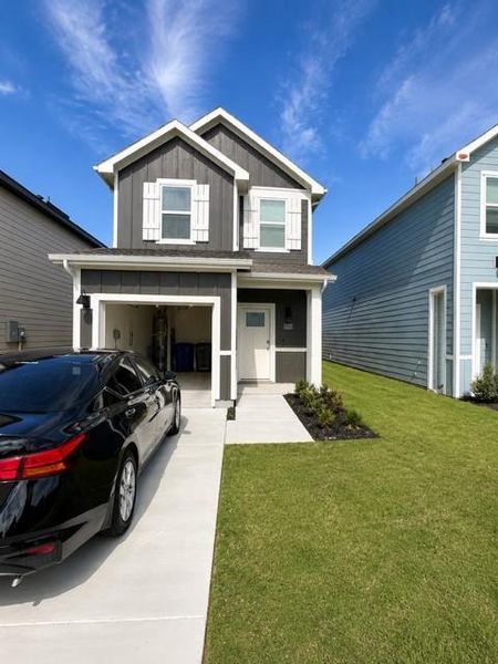 Two-story residence featuring a dark gray facade with white trim, a single-car garage, and a concrete driveway Two-story residence featuring a dark gray facade with white trim, a single-car garage, and a concrete driveway
