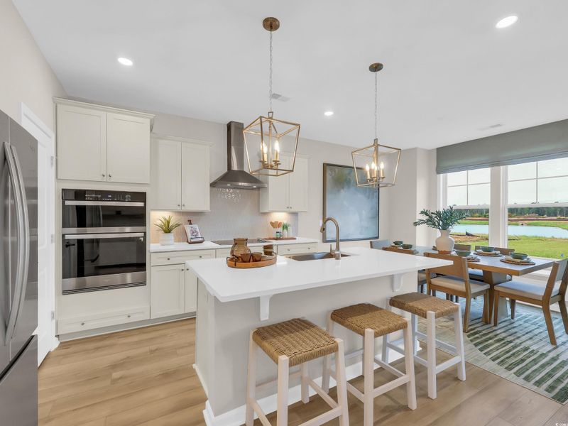 Kitchen with decorative light fixtures, backsplash, light wood-style flooring, appliances with stainless steel finishes, and recessed lighting