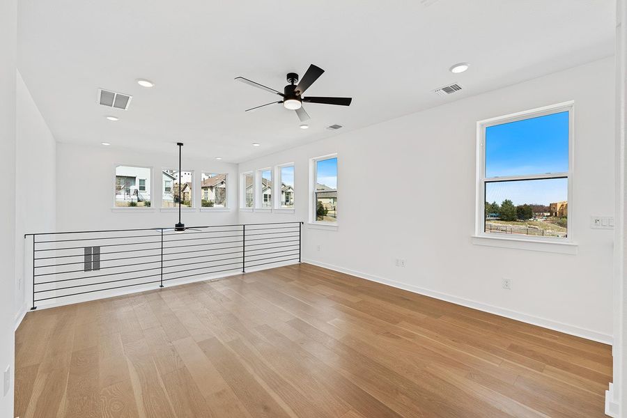 Second floor game room or flex space with modern horizontal railing, natural light and wood floors