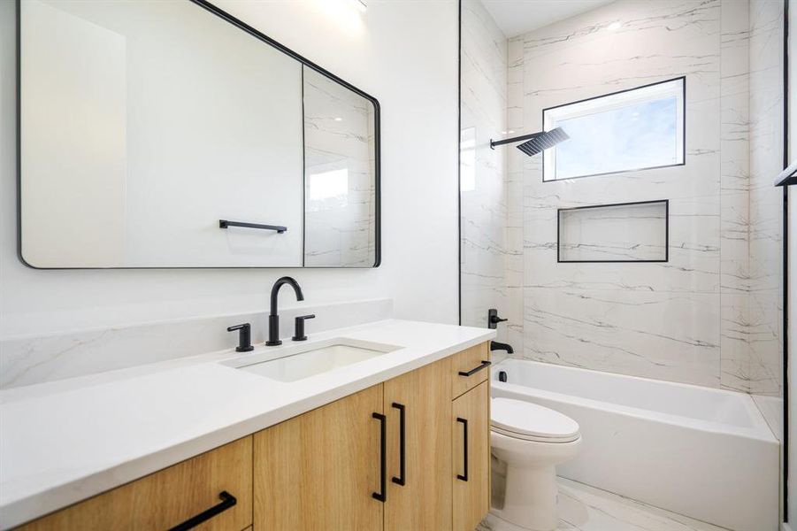 Full bathroom with toilet, vanity, and tiled shower / bath combo