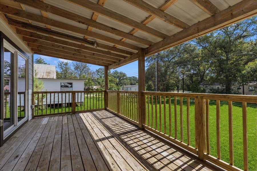 A wooden deck with a covered roof overlooks the spacious green yard. A wooden deck with a covered roof overlooks the spacious green yard.