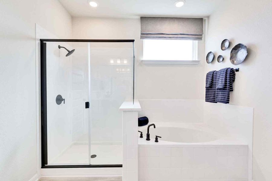 A well-lit primary bathroom featuring a spacious walk-in shower and a built-in soaking tub.