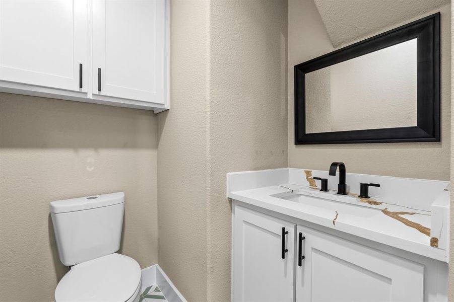 Vanity with white shaker cabinetry, gold-veined countertop, and matte black faucet