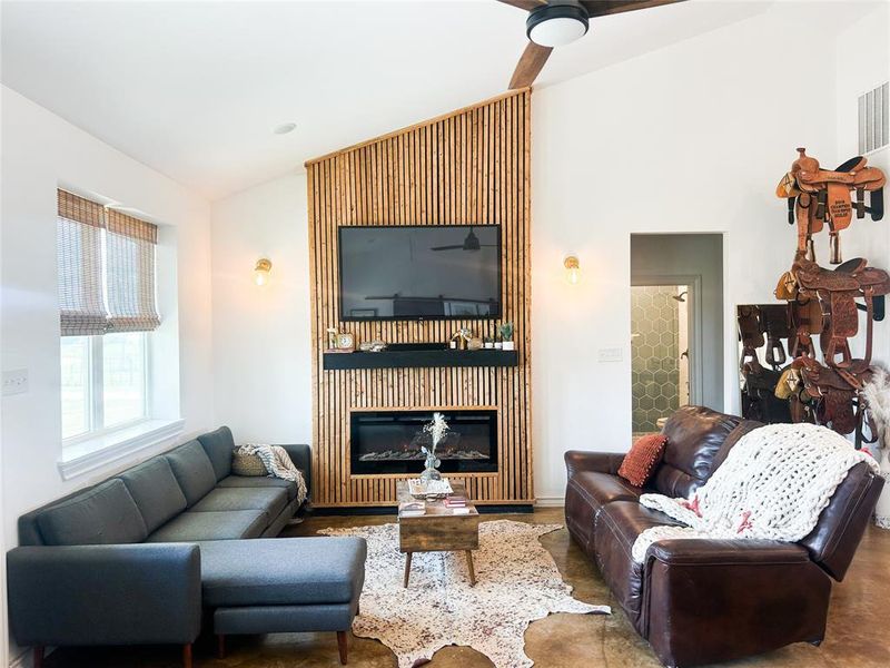 Living area featuring lofted ceiling, a glass covered fireplace, and a ceiling fan Living area featuring lofted ceiling, a glass covered fireplace, and a ceiling fan