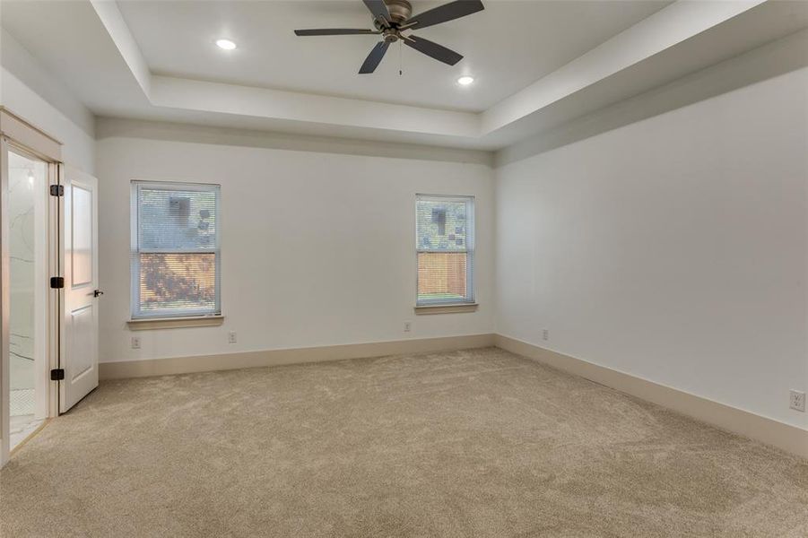 Carpeted empty room with a tray ceiling, a ceiling fan, and recessed lighting Carpeted empty room with a tray ceiling, a ceiling fan, and recessed lighting