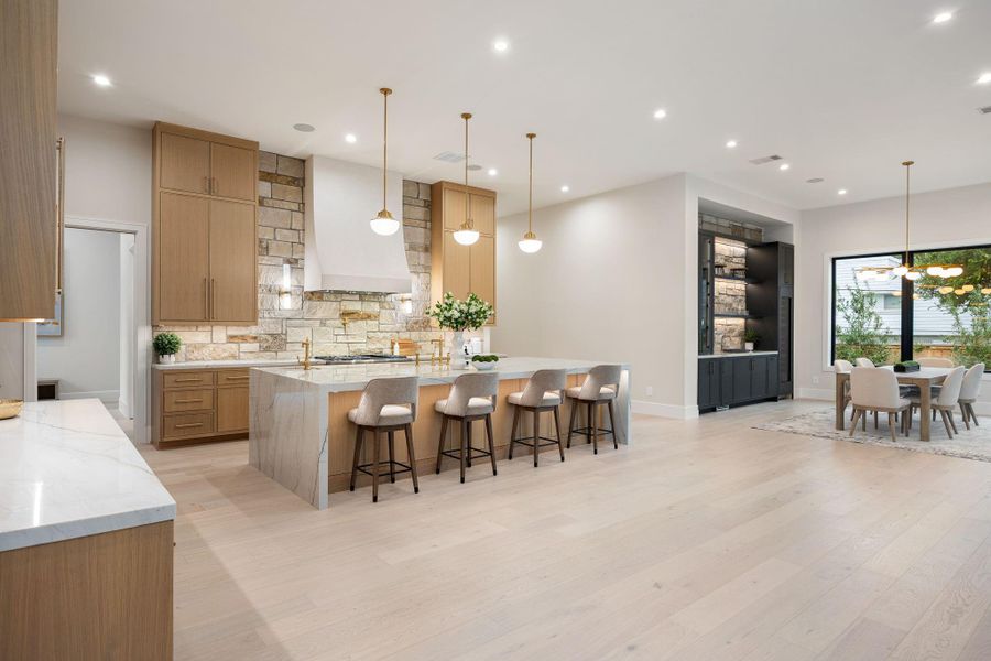 This wide-angle view captures the full scale of the kitchen, where thoughtful design meets everyday functionality. The large island anchors the space, complemented by soft lighting and clean architectural lines. The standout element is the balance of openness and defined areas, creating a space that feels both expansive and welcoming for gatherings or quiet moments.