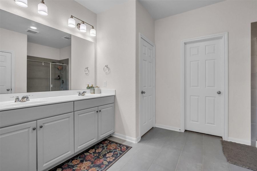 The spacious primary bathroom features a double-sink vanity and a walk-in shower, providing a practical and comfortable space for everyday routines.