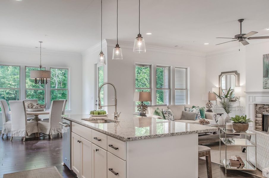 Kitchen with ornamental molding, light stone counters, white cabinetry, dark wood finished floors, and open floor plan Kitchen with ornamental molding, light stone counters, white cabinetry, dark wood finished floors, and open floor plan