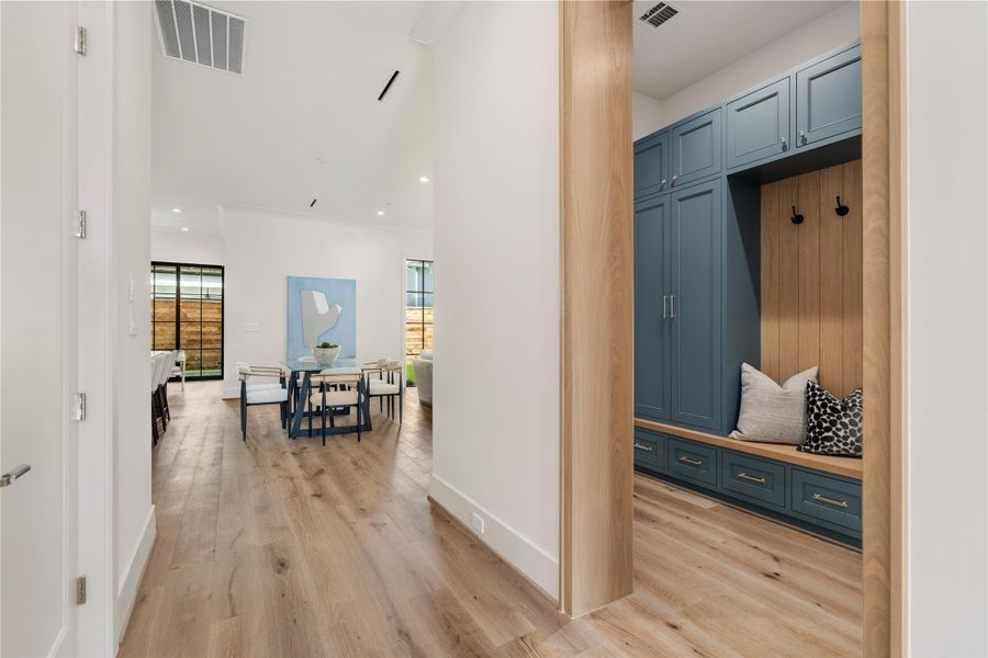 The mud room between the garage and main living area houses a tongue & groove white oak bench, great for taking off boots or lacing up sneakers. Floor-to-ceiling cabinetry will house outwear, sports gear, and more with ease. The dark blue tones complement the oak nicely.