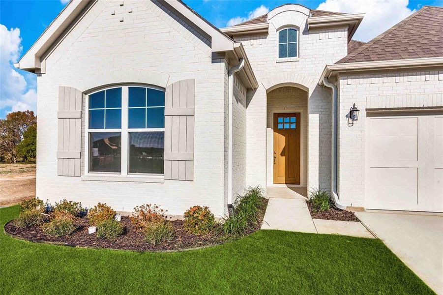 View of exterior entry featuring a lawn and a garage