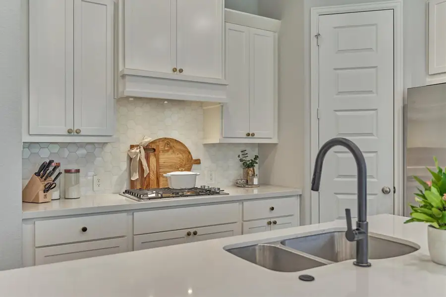 Fantastic kitchen w/ hexagon shaped tile backsplash, brushed gold hardware, garbage disposal air-switch, matte black pull down spray faucet, large island w/ storage and seating, huge walk-in pantry.