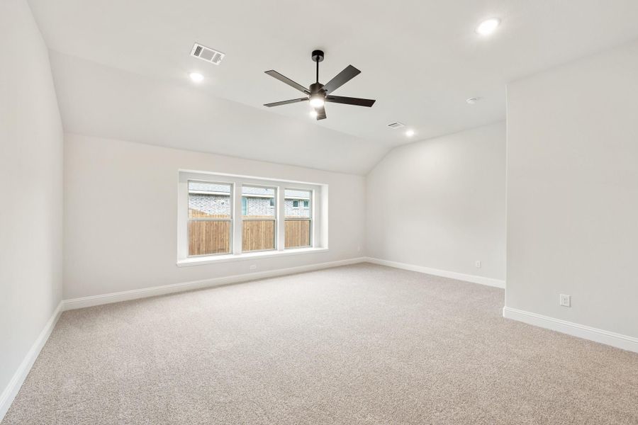 Empty bedroom with vaulted ceiling, ceiling fan, carpet flooring, and large window