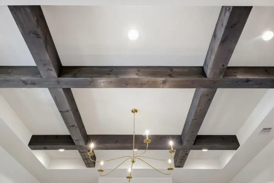 Detailed view of the ceiling featuring decorative wood beams, recessed lighting, and a chandelier with multiple light fixtures