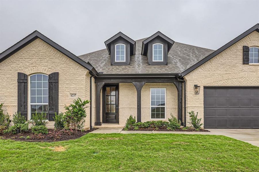 View of front of home with a garage and a front lawn